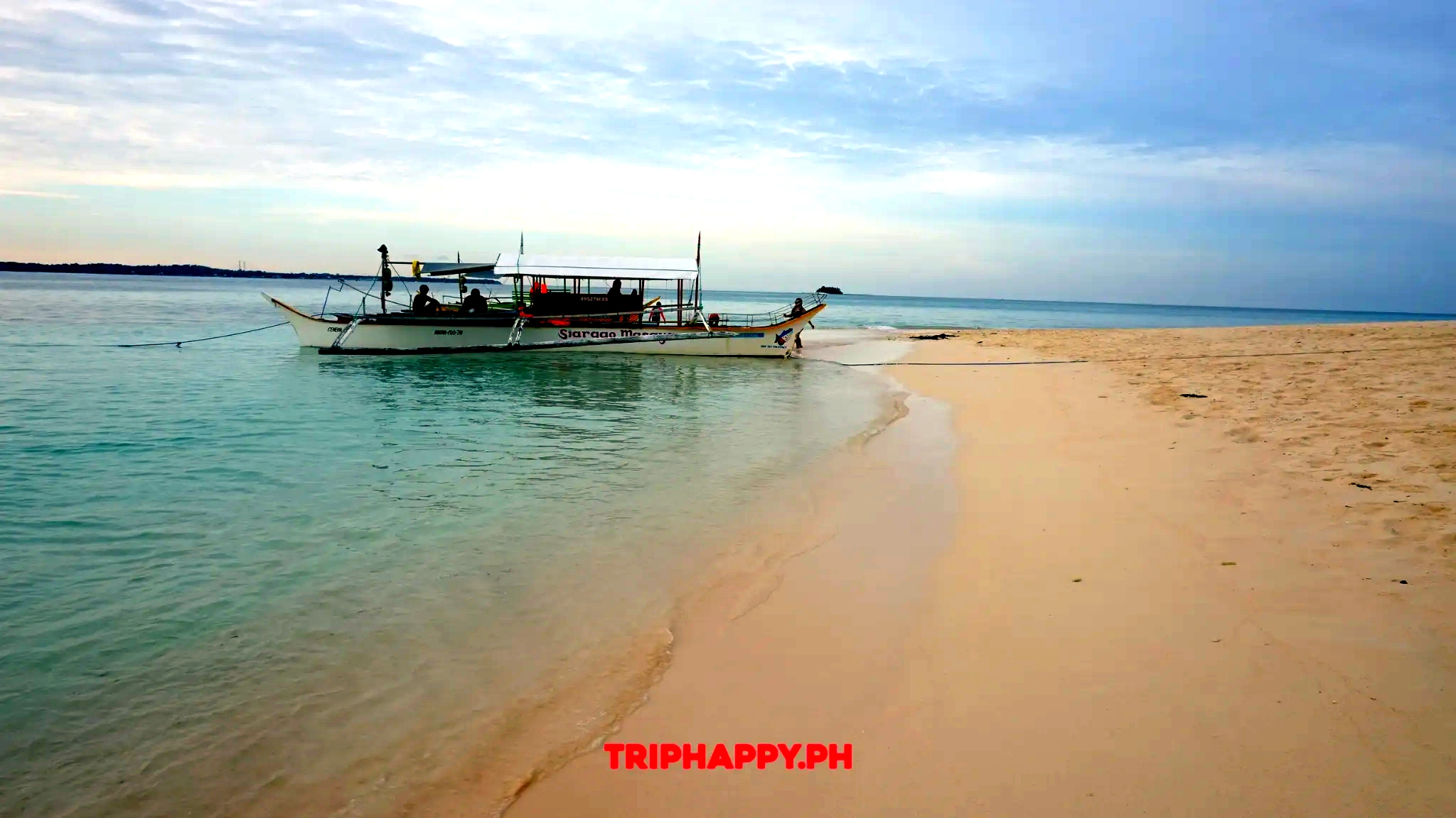 Relax on the sandy shore while enjoying the calm waters and traditional boats.