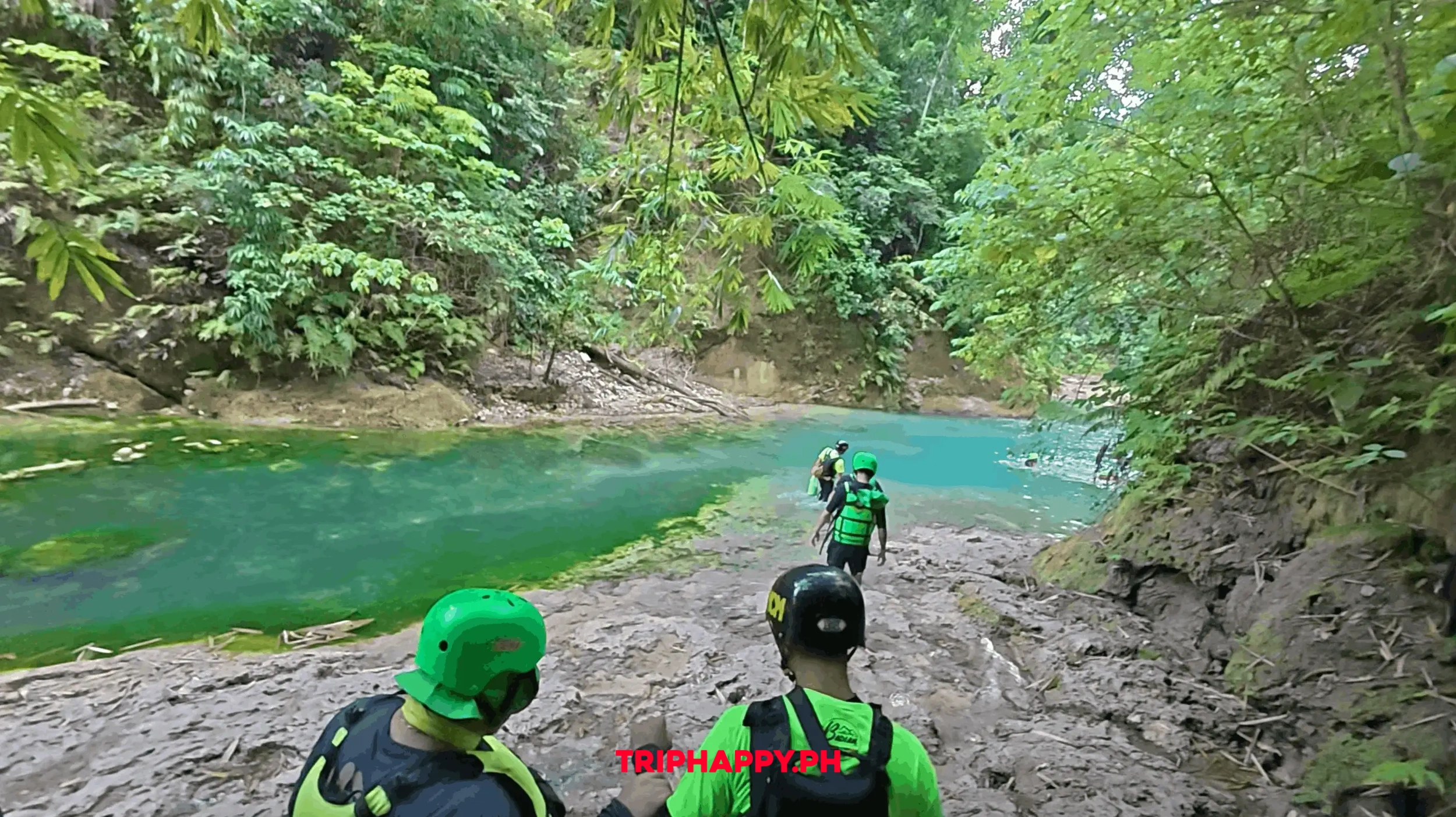 Participants trekking through the turquoise river during the Kawasan Falls adventure.