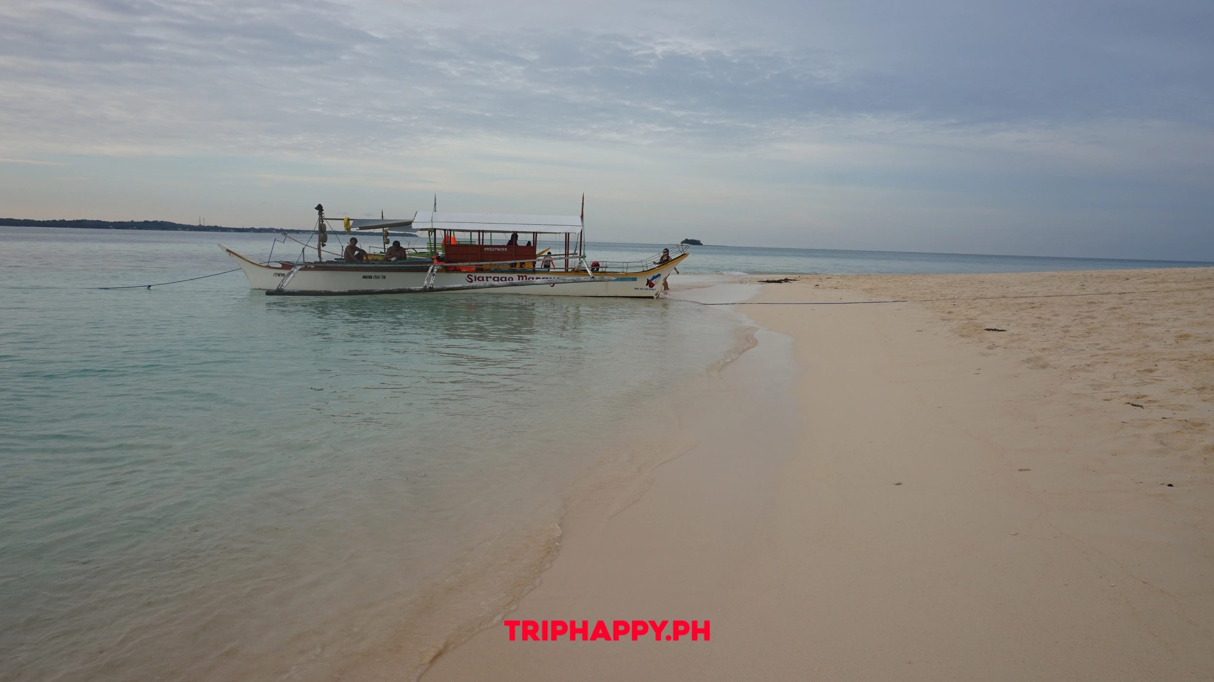 See traditional boats resting along the calm island waters.
