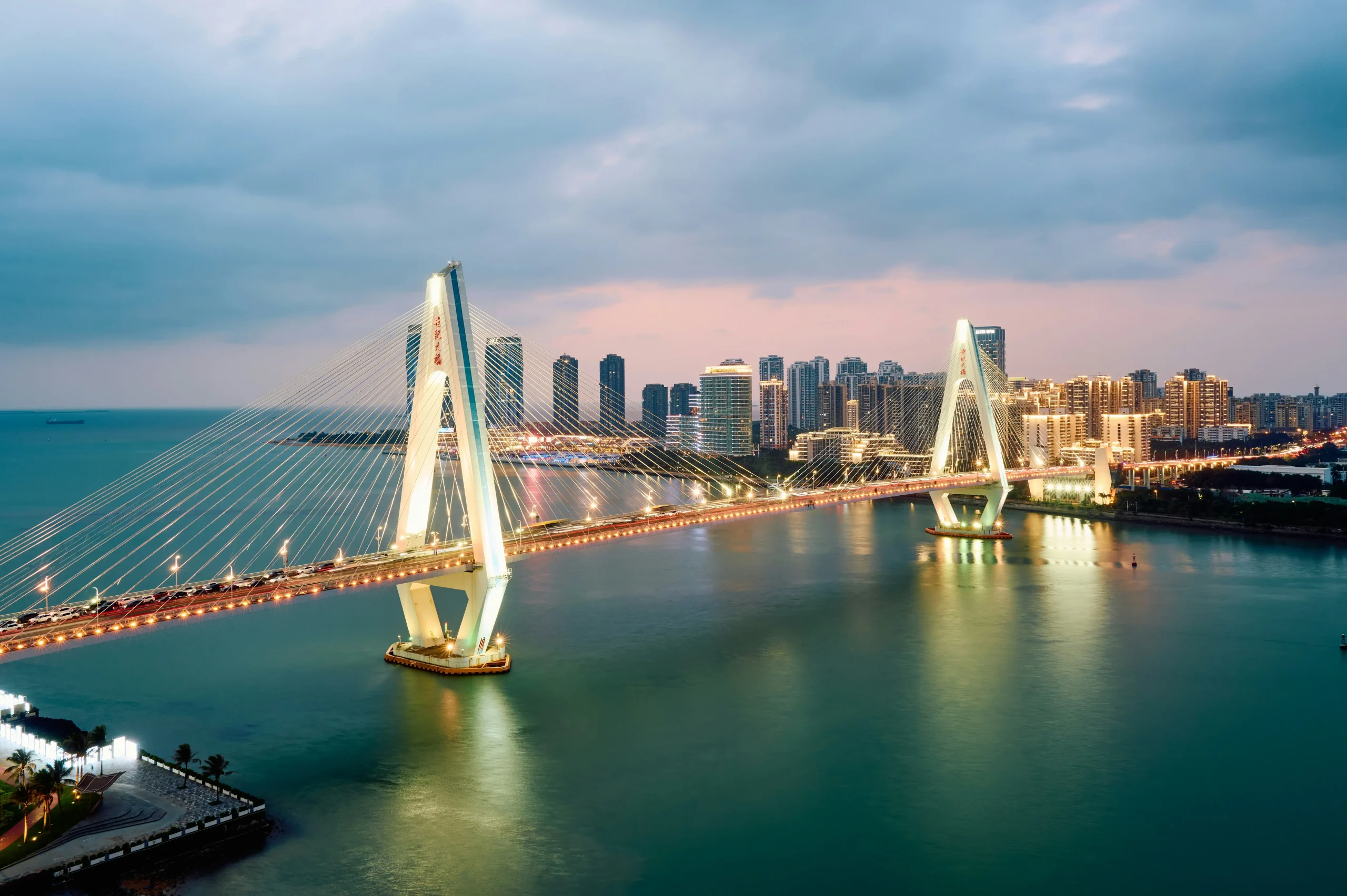 Sanya Hainan waterfront with illuminated bridge at sunset